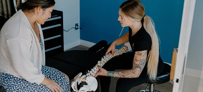 Chiropractor Jenna Swaffer Pointing To Spine With Patient